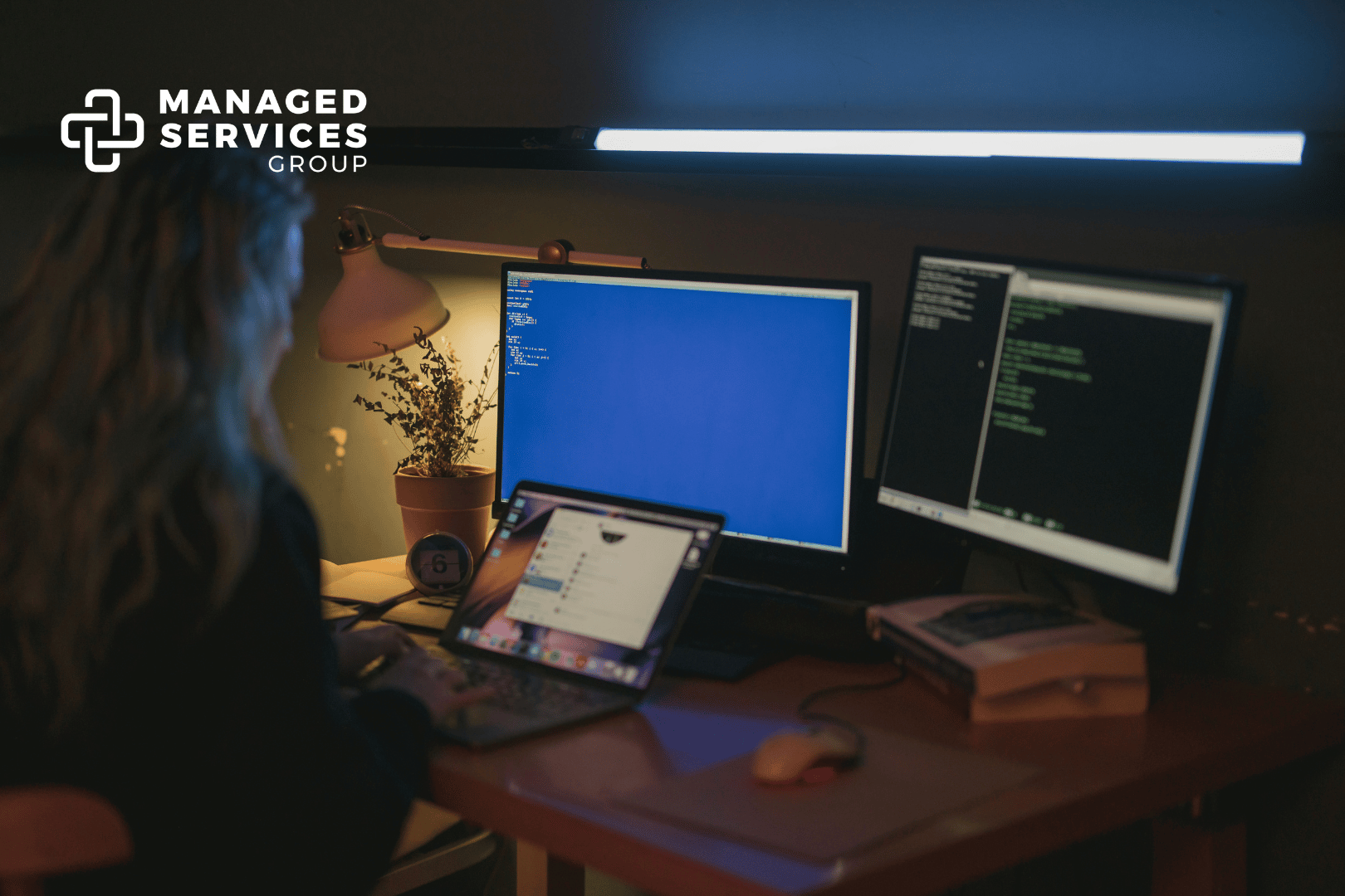 Managed Services Group - Working on computer with dim lighting