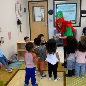 Giving children candy in a classroom dressed as an elf
