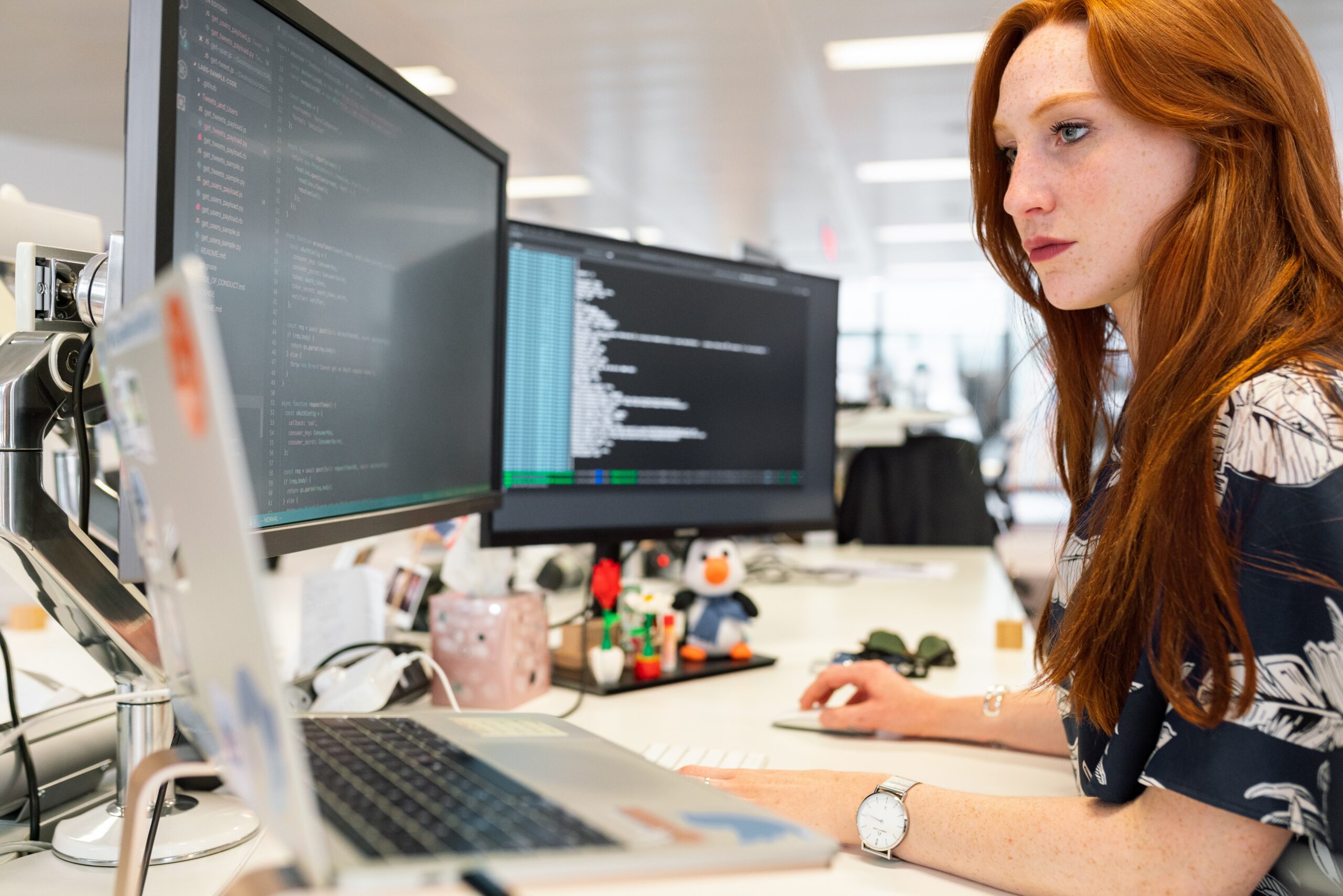 Lady working at desk laptop with multiple monitors